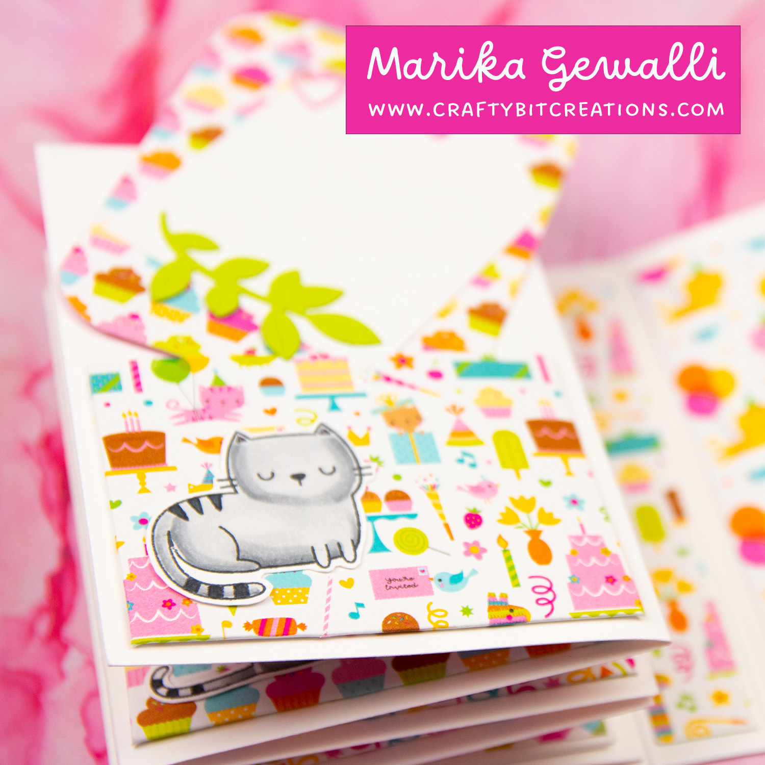 Close up of page of accordion album showing to tags and angled pockets made out of pattern paper. all decorated with stamped and colored images of cats and greenery.