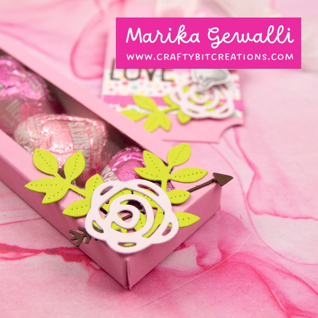 close up mid pink decorated box with 4 hershey's hearts inside and a coordinating tag