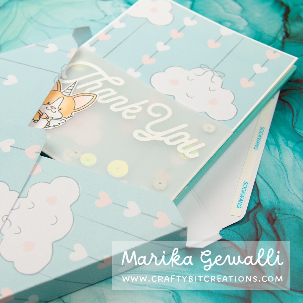 Close up images of a blue-green box card covered in pattern paper with clouds and strings of hearts. The card sticks out of an envelope.