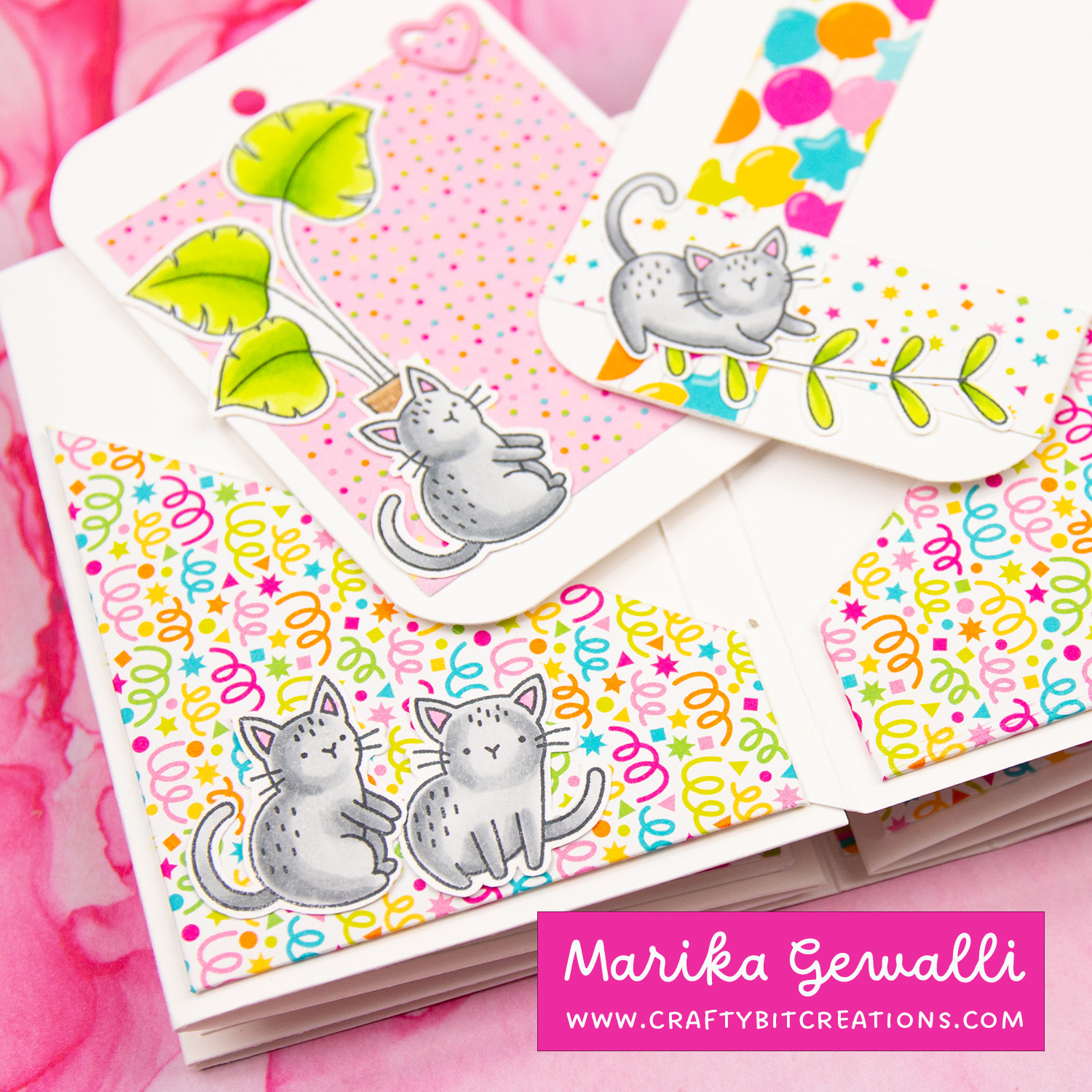 Close up of second spread of accordion album showing to tags and angled pockets made out of pattern paper. all decorated with stamped and colored images of cats and greenery.