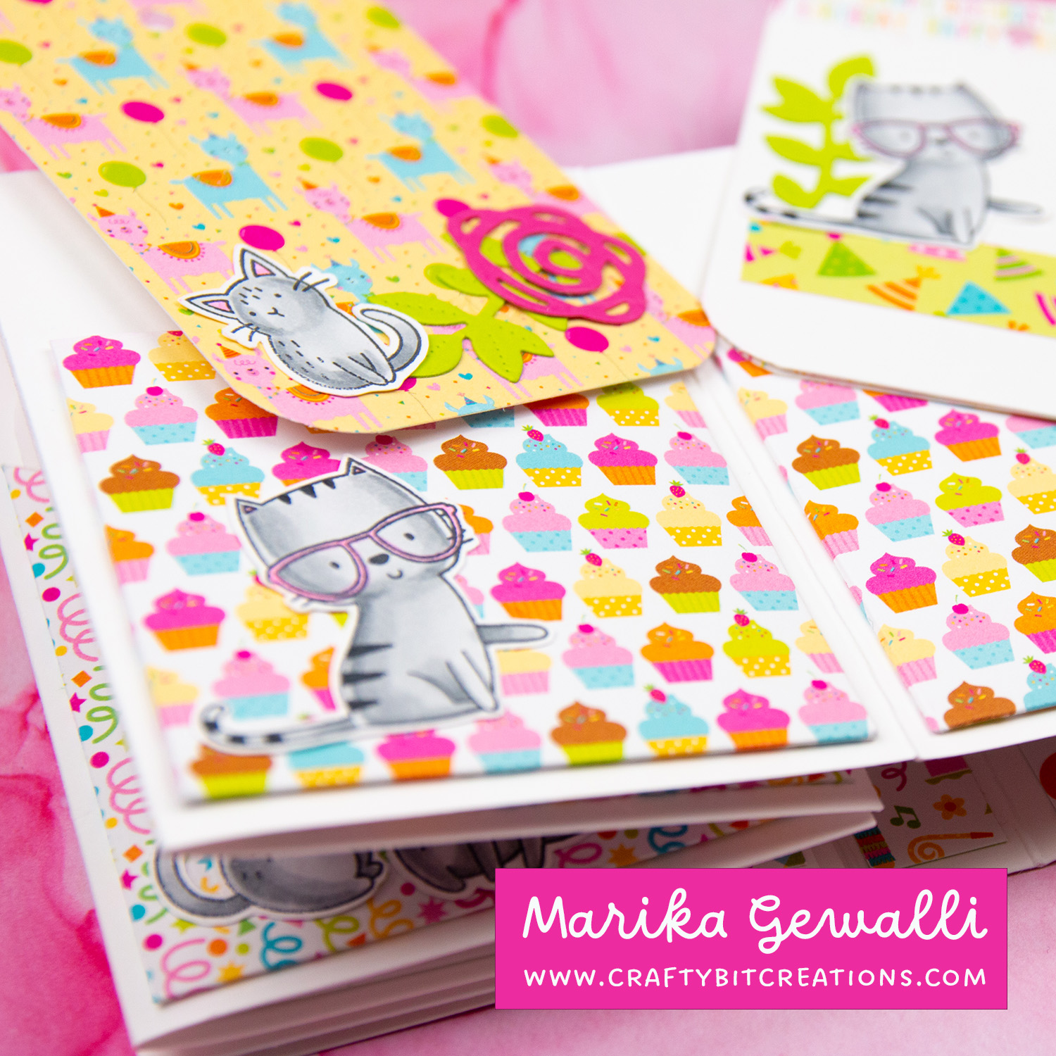 Close up of third spread of accordion album showing to tags and pockets made out of pattern paper. all decorated with stamped and colored images of cats and greenery.