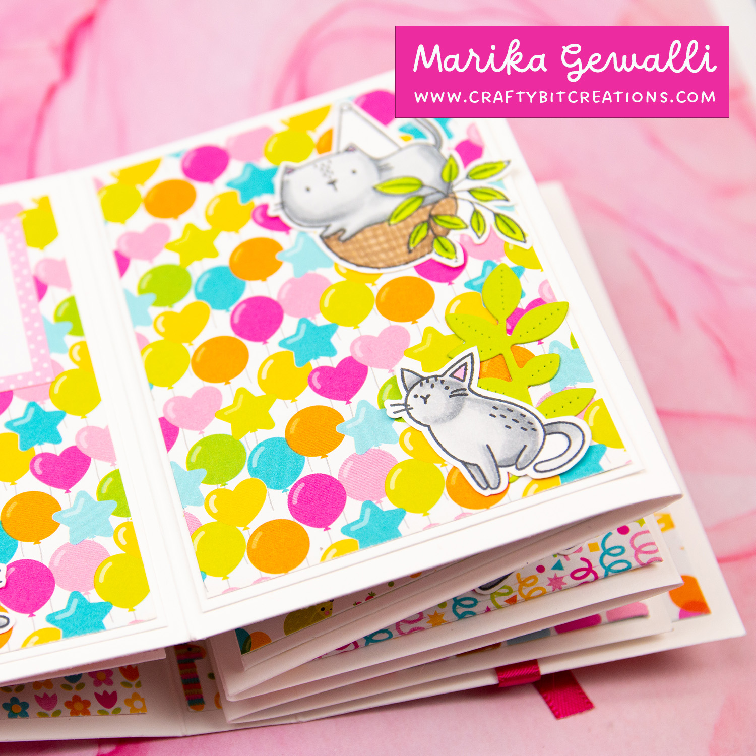 Close up of first spread of accordion album showing pattern paper with different shaped balloons on and two stamped, colored and cut cats.