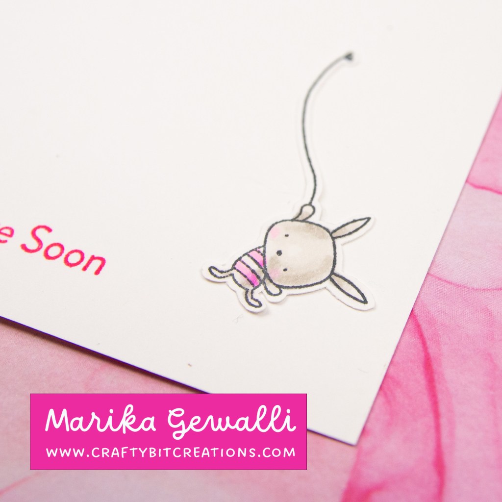 close up of copic colored bunny hanging in a string, grey with pink striped shirt