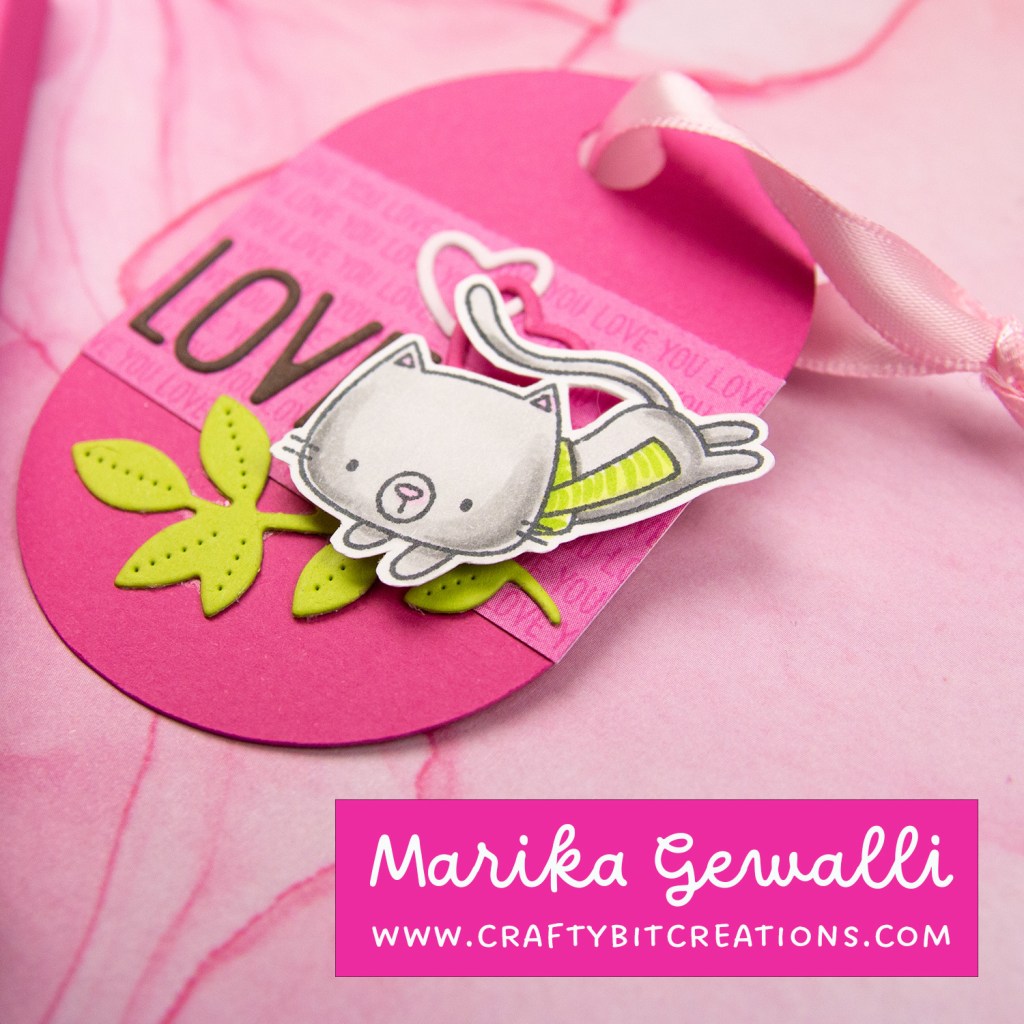 close up coordinating tag showing the text love and a diecut branch layered under a stamped and colored cat